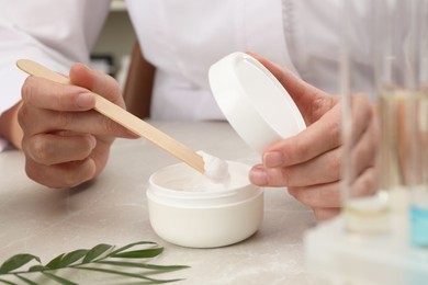 Dermatologist developing cosmetic product at light marble table, closeup