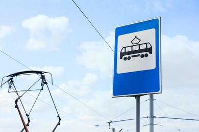 Tram stop sign against blue sky. Space for text