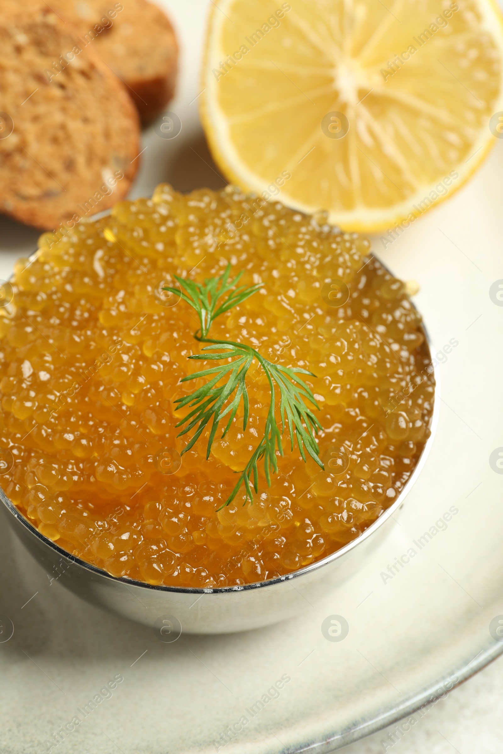 Photo of Fresh pike caviar in bowl, lemon and bread on table, closeup