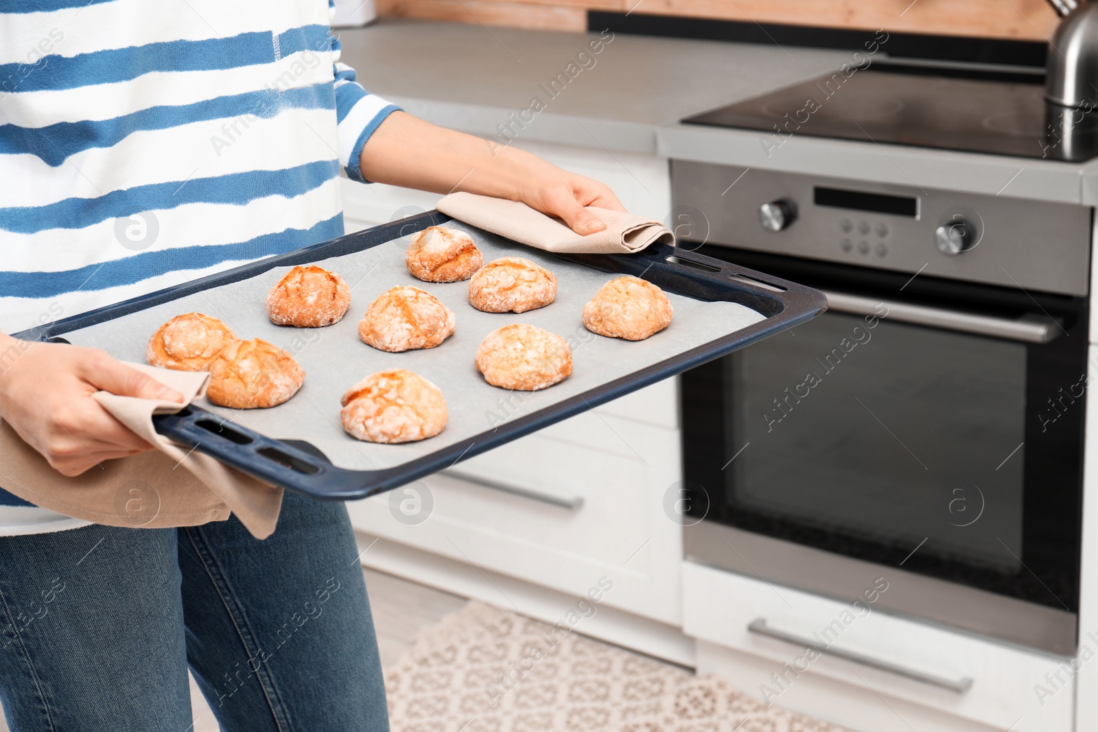 Photo of Young woman with sheet pan of oven baked cookies in kitchen, closeup