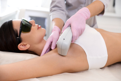 Photo of Young woman undergoing laser epilation procedure in beauty salon