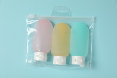 Photo of Cosmetic travel kit in plastic bag on light blue background, top view. Bath accessories