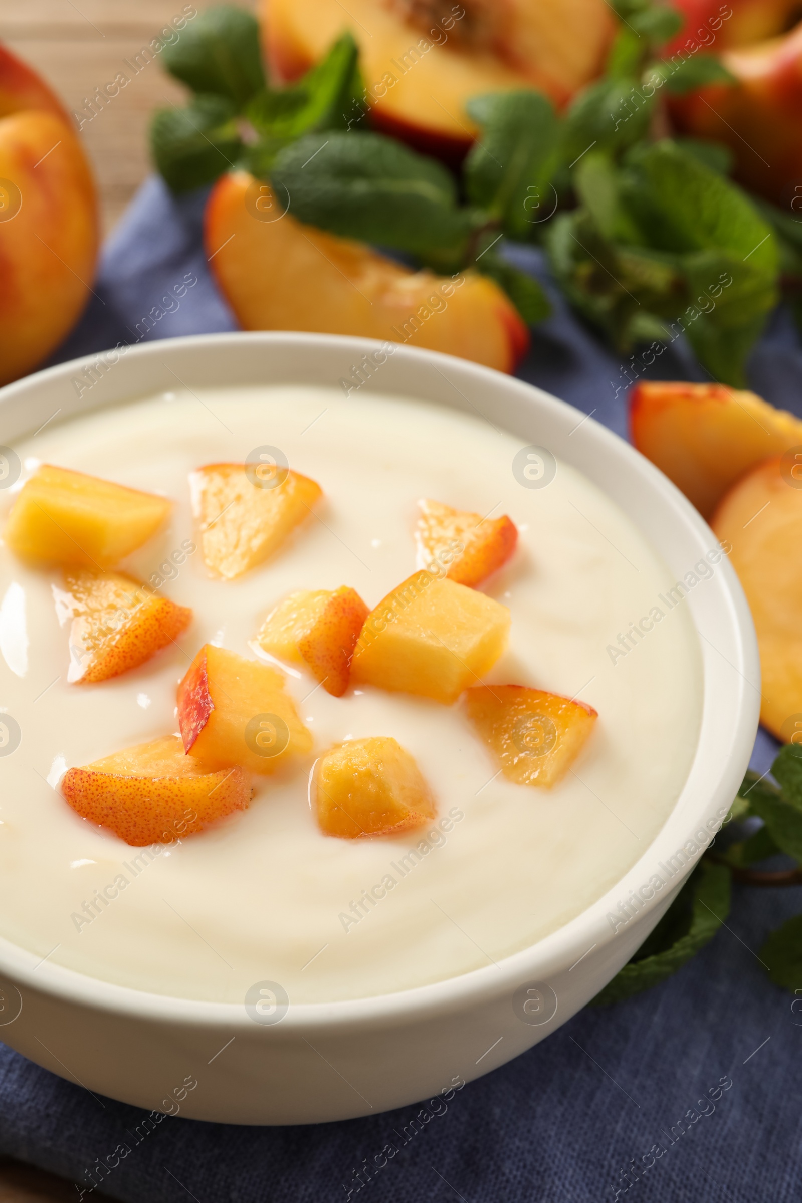 Photo of Delicious yogurt with fresh peach on table, closeup