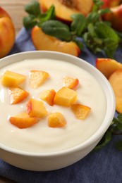 Photo of Delicious yogurt with fresh peach on table, closeup