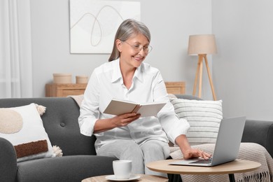 Photo of Beautiful senior woman with notebook using laptop at home