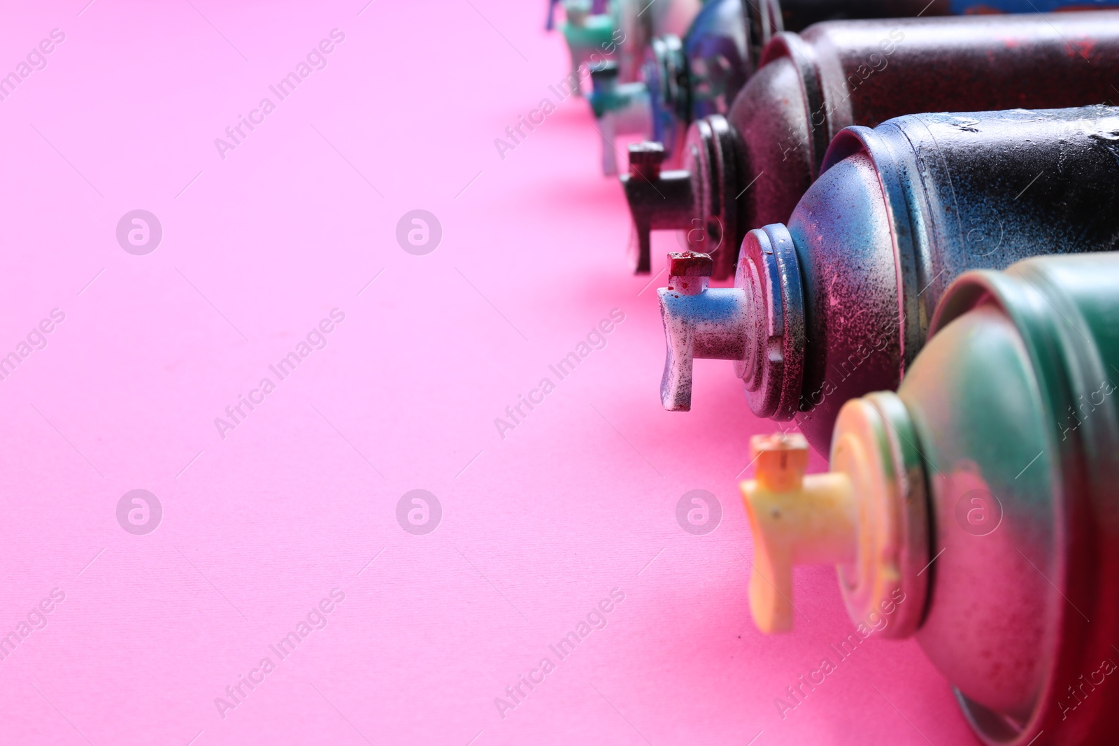 Photo of Many spray paint cans on pink background, closeup. Space for text