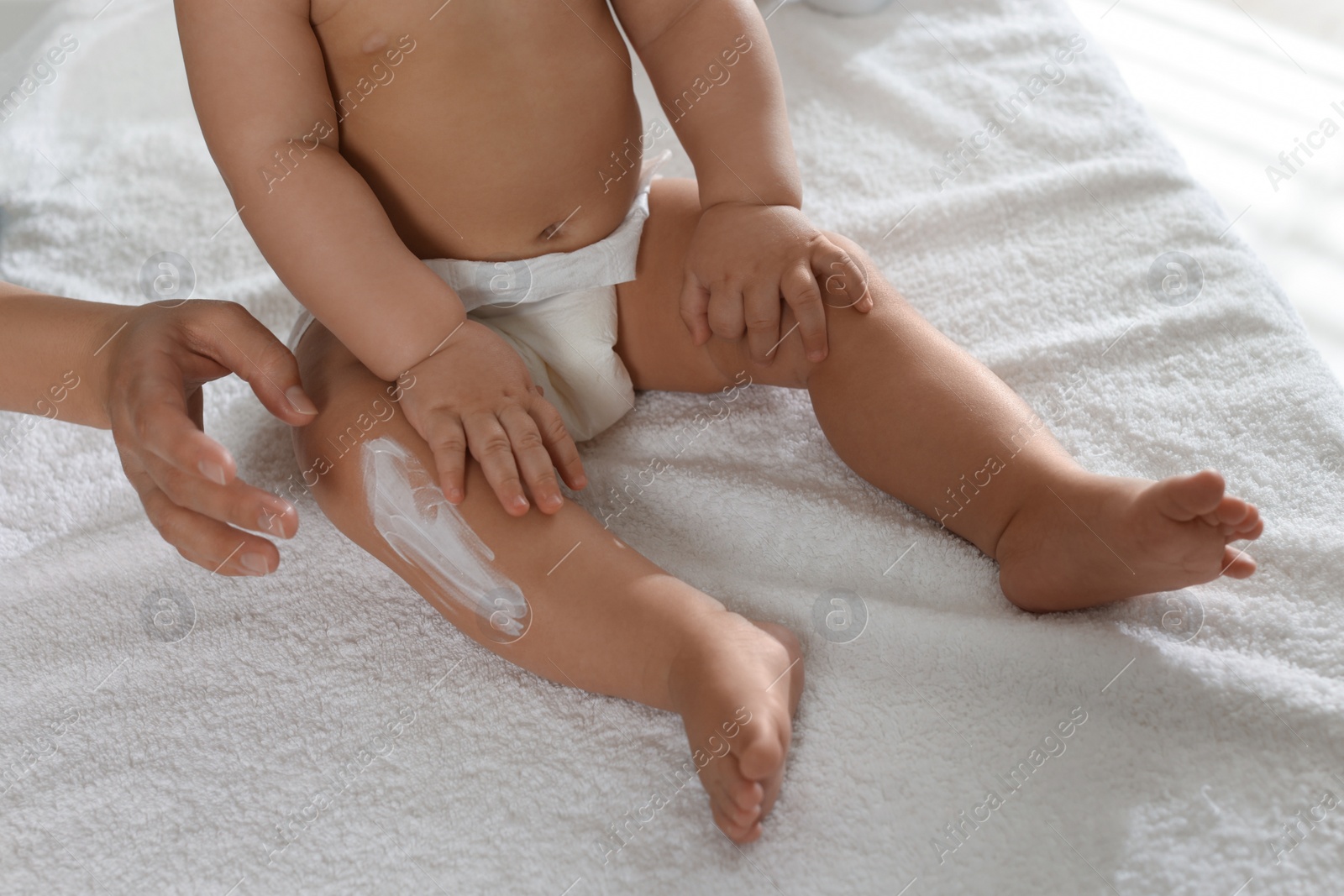 Photo of Mother applying body cream on her little baby, closeup