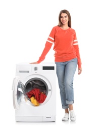 Young woman near washing machine with laundry on white background