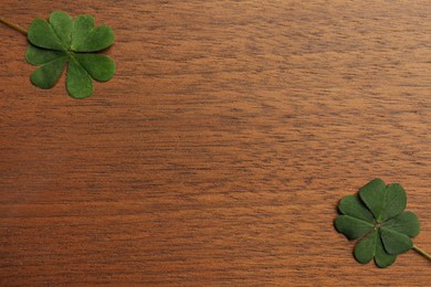 Photo of Green clover leaves on wooden background, flat lay. Space for text
