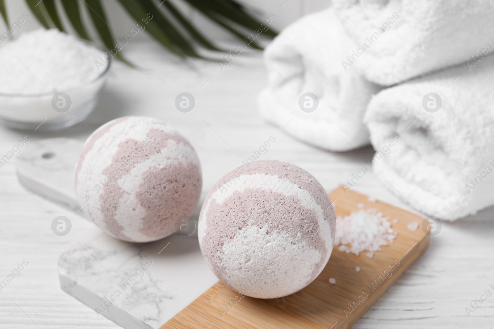 Photo of Bath bombs, sea salt and rolled towels on white wooden table