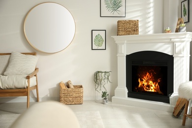 Photo of Bright living room interior with artificial fireplace and firewood in basket