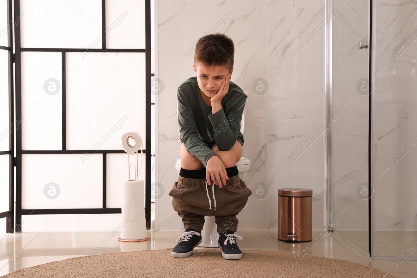 Photo of Boy suffering from hemorrhoid on toilet bowl in rest room