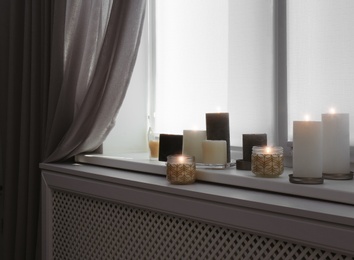 Photo of Burning candles on window sill in room