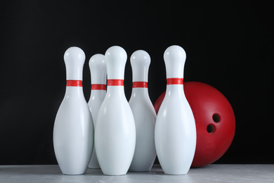 Photo of Red bowling ball and pins on grey stone table