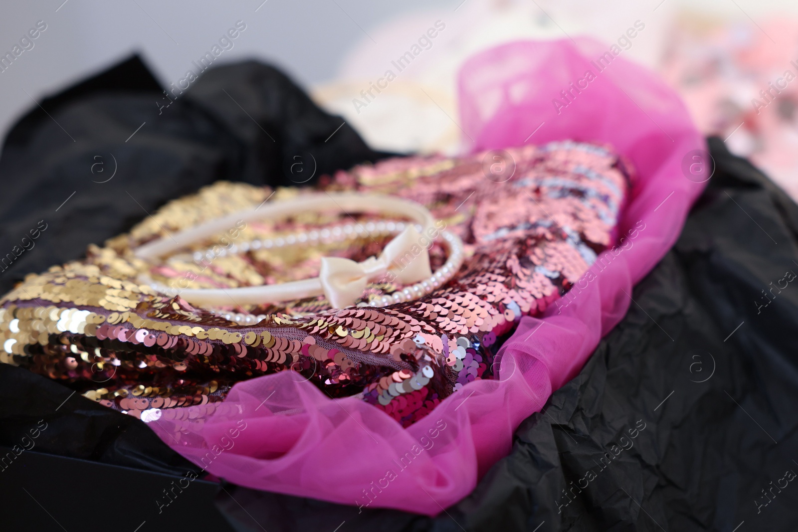 Photo of Headbands and stylish pink carnival costume with sequins in black box, closeup