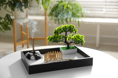 Photo of Beautiful miniature zen garden with incense sticks on table indoors