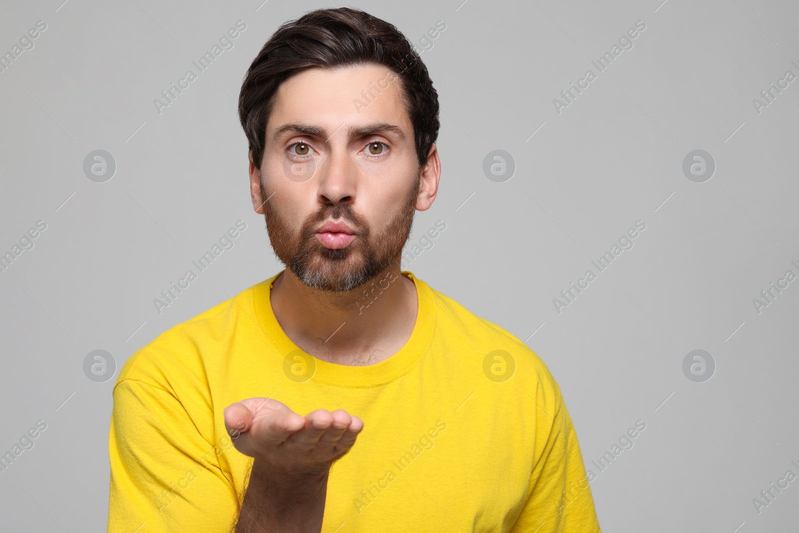 Photo of Handsome man blowing kiss on light grey background. Space for text