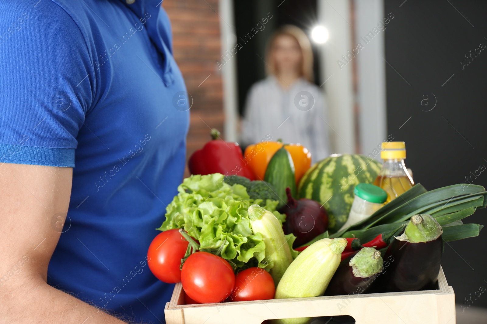 Photo of Courier with fresh products indoors, closeup. Food delivery service