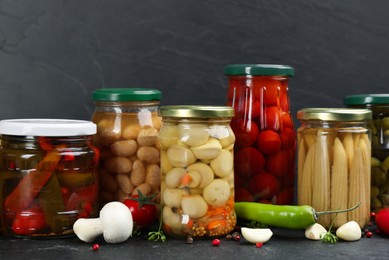 Jars of pickled vegetables on grey background