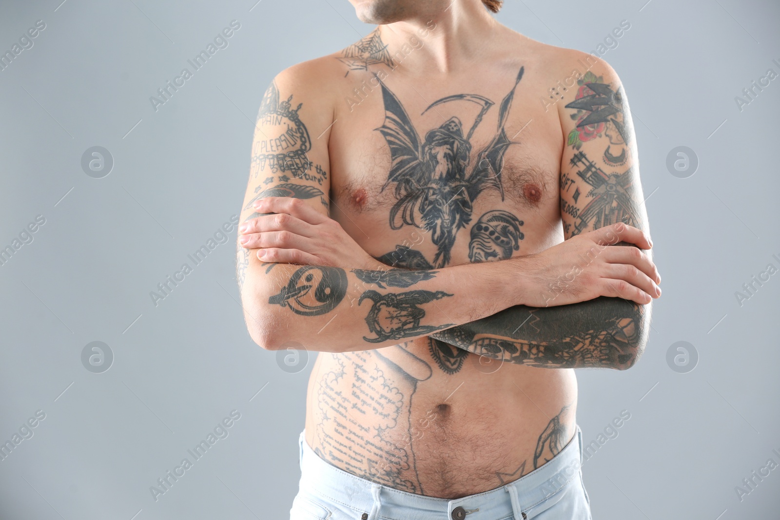 Photo of Young man with stylish tattoos on grey background