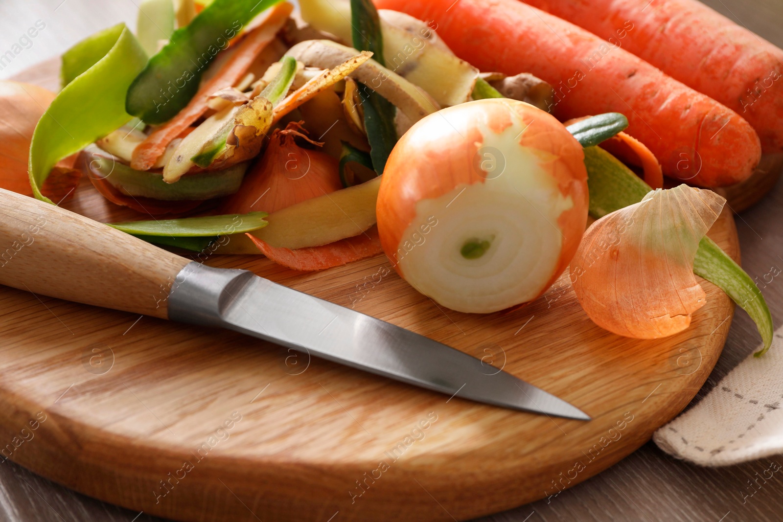 Photo of Peels of fresh vegetables and knife on table, closeup