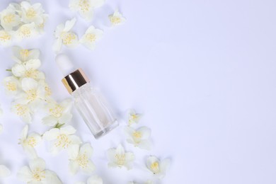 Essential oil in bottle and beautiful jasmine flowers on white background, flat lay. Space for text