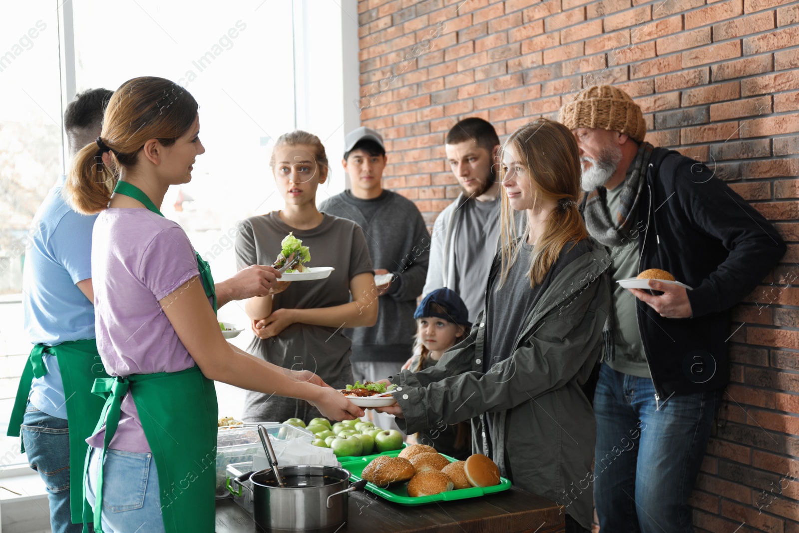 Photo of Volunteers giving food to poor people indoors