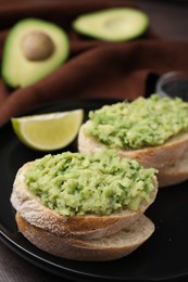 Photo of Delicious sandwiches with guacamole on black plate, closeup