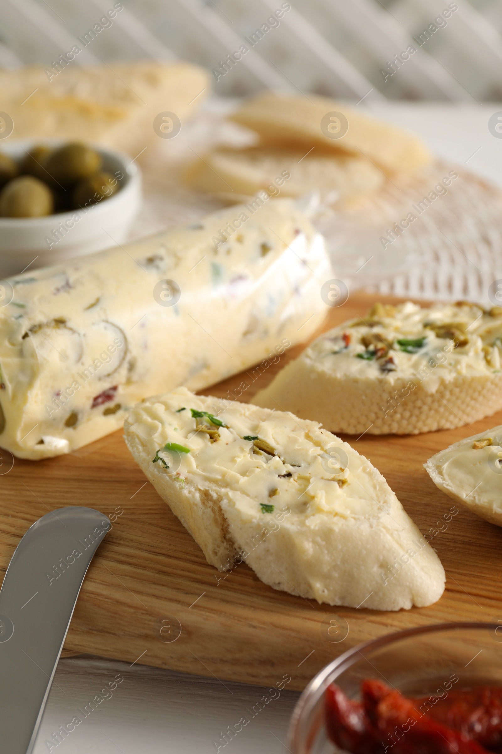 Photo of Tasty butter with olives, green onion and bread on table, closeup