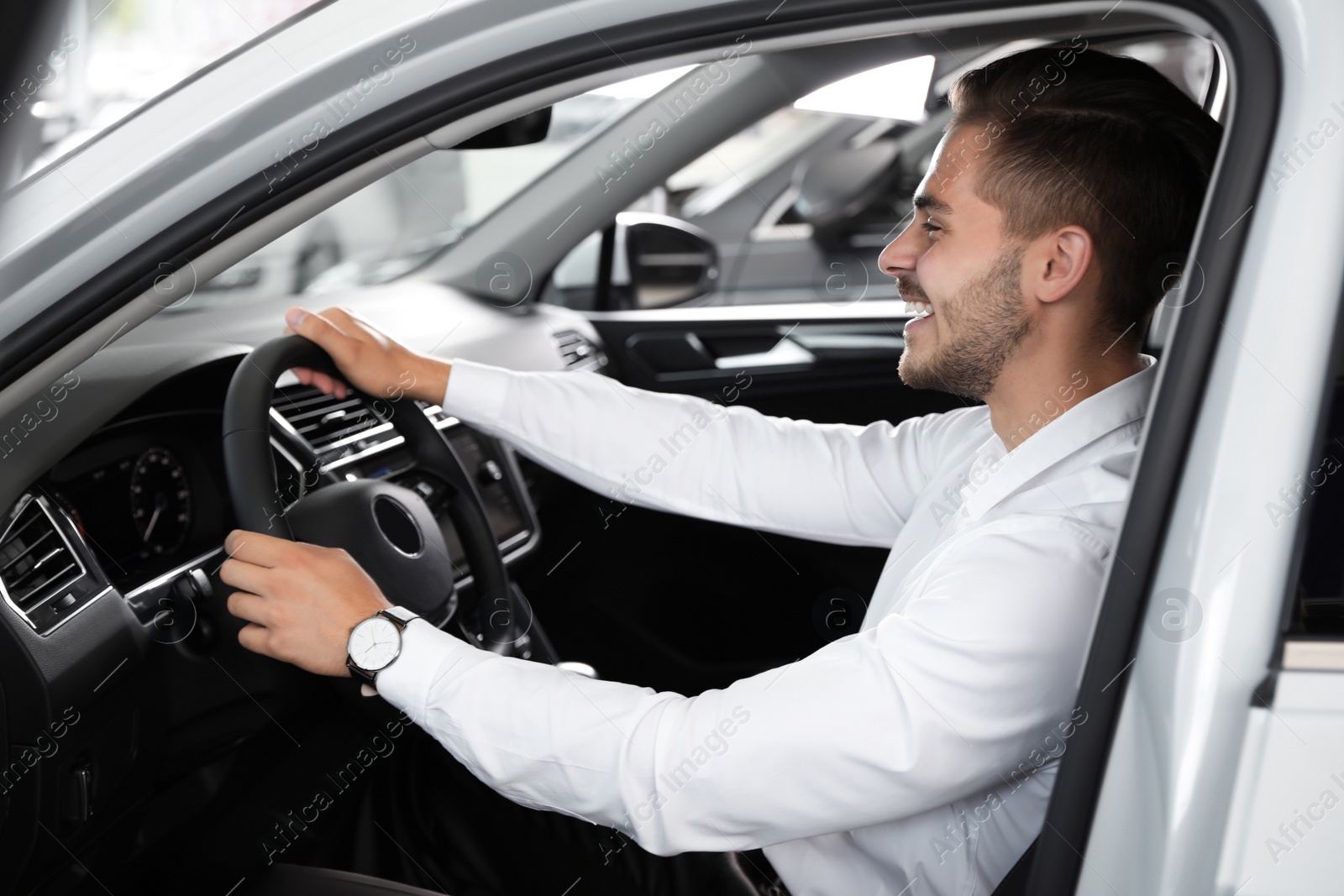 Photo of Young man testing new car in salon