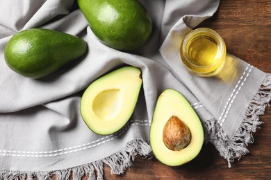 Photo of Jar with oil and ripe fresh avocados on table, top view