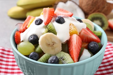 Photo of Delicious fruit salad with yogurt in bowl on table, closeup