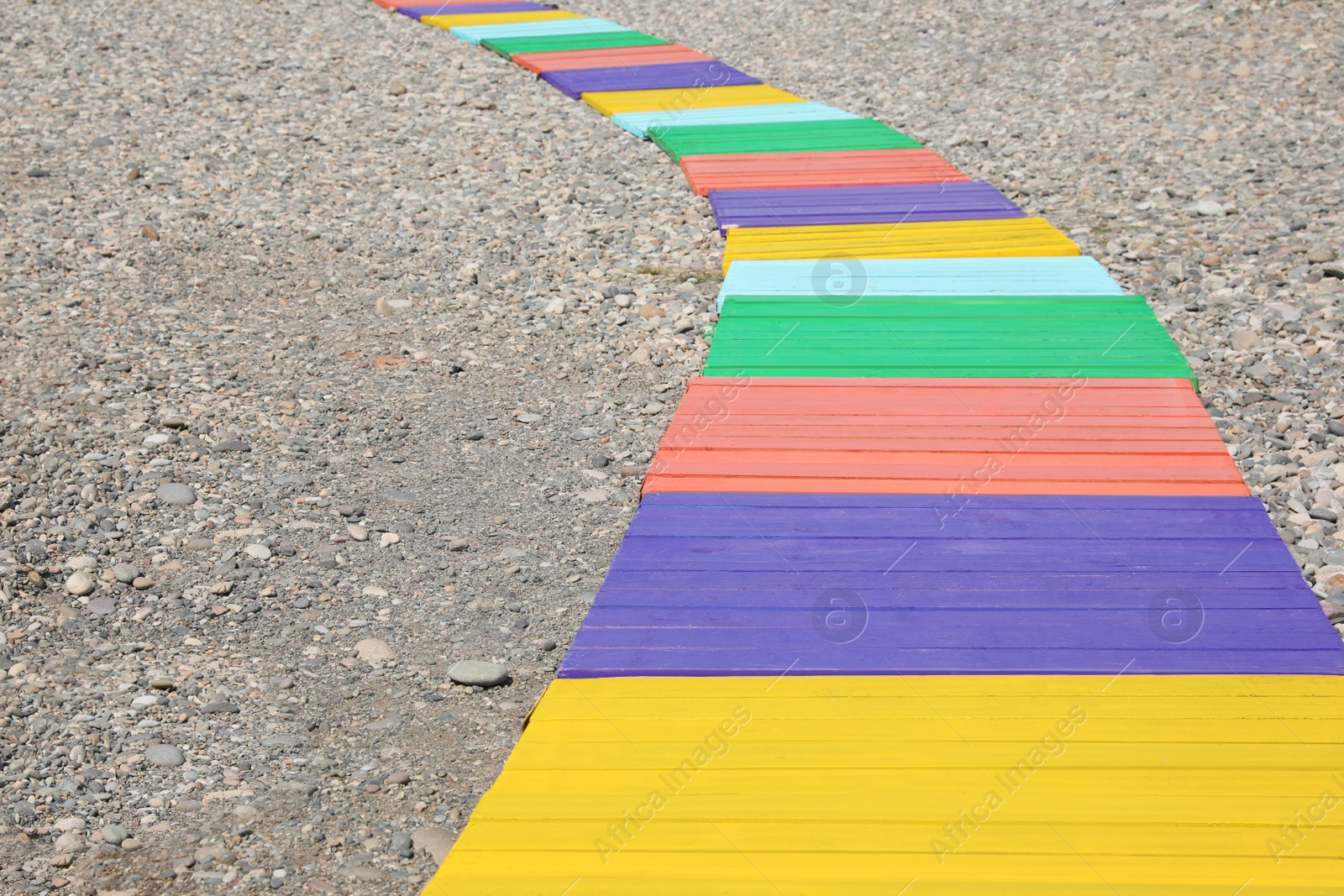 Photo of Colorful wooden walkway on pebble beach. Space for text