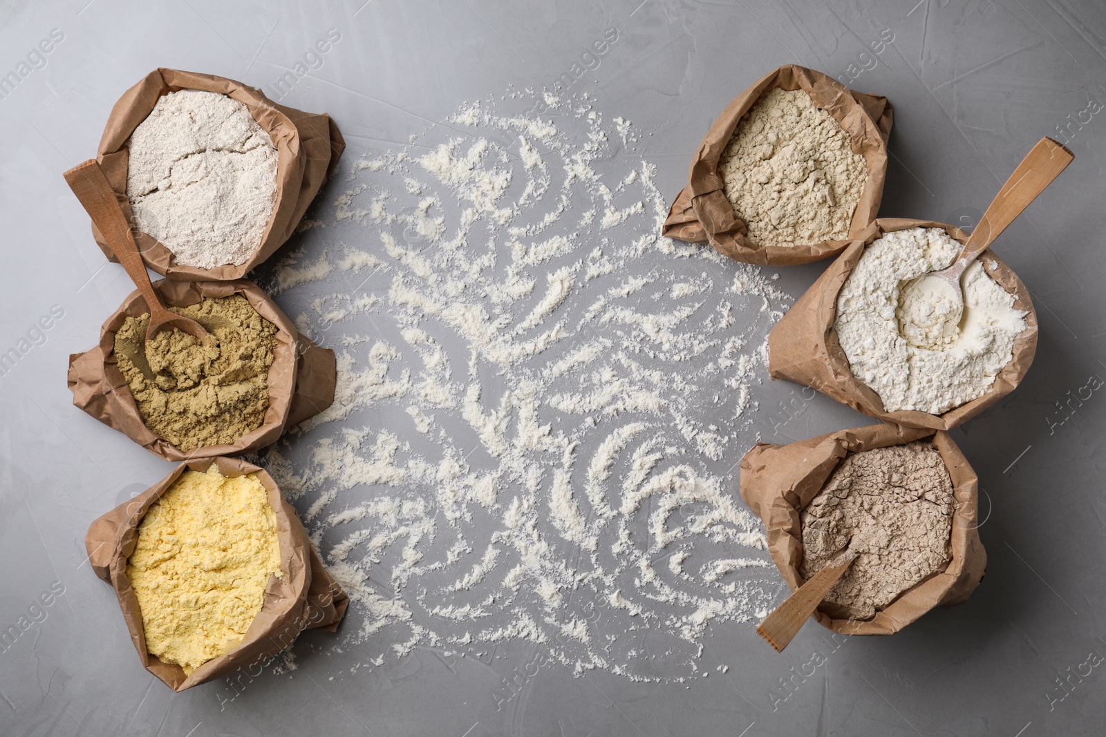 Photo of Paper bags with different types of flour on gray background