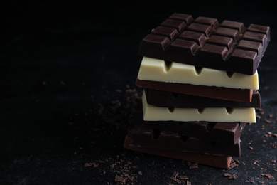 Photo of Different tasty chocolate bars on black table. Space for text