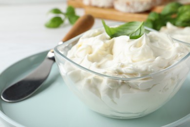 Photo of Tasty cream cheese with basil and knife on white table, closeup