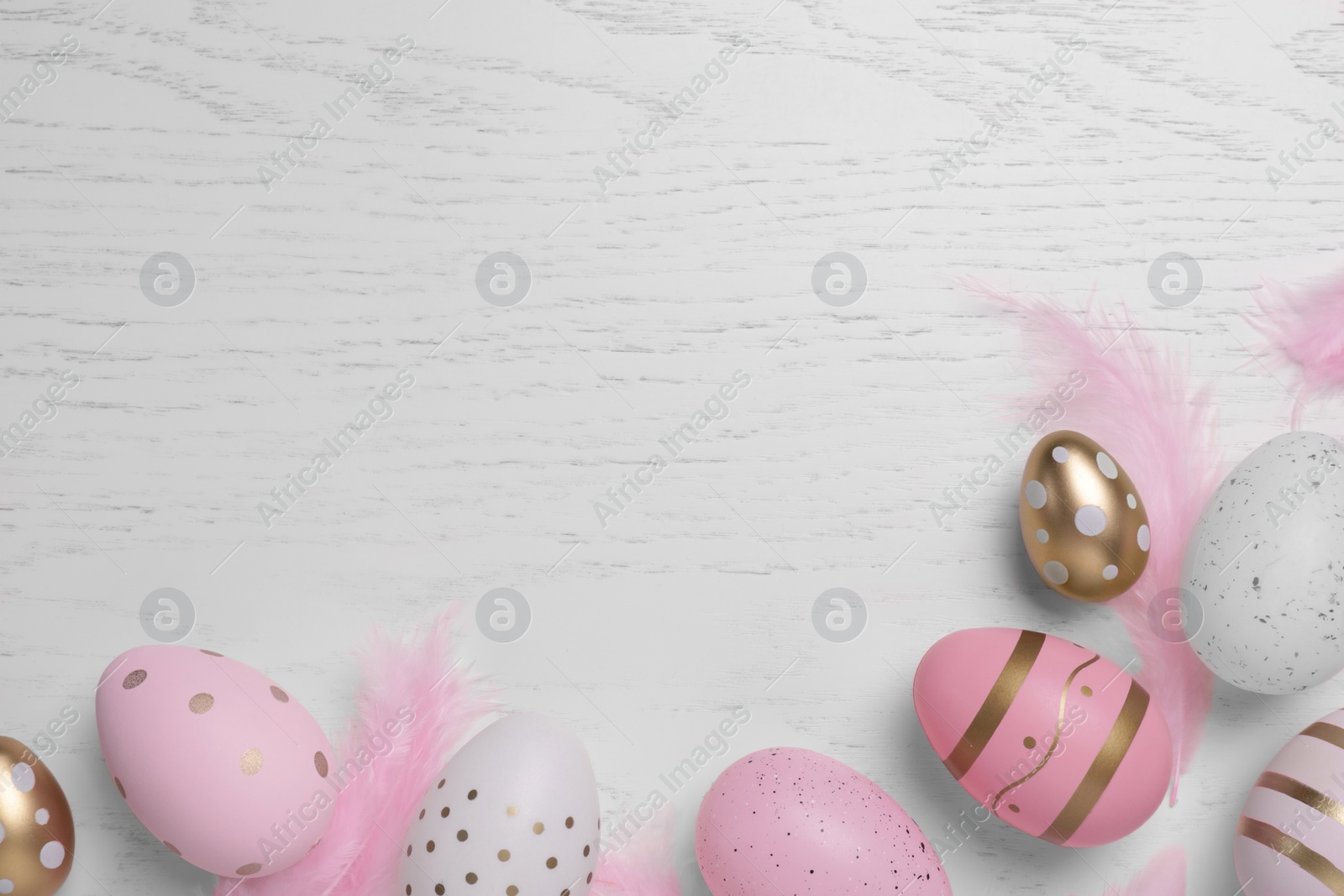 Photo of Flat lay composition with festively decorated Easter eggs on white wooden table. Space for text