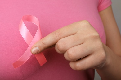 Photo of Woman holding pink ribbon, closeup. Breast cancer awareness