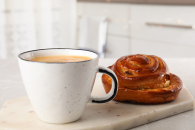 Photo of Delicious bun and coffee on light table. Sweet pastries