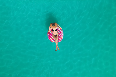 Young happy woman with inflatable ring in swimming pool, top view. Summer vacation