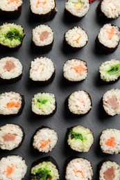 Tasty sushi rolls on black table, flat lay