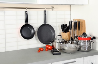 Photo of Set of clean cookware and utensils on table in modern kitchen