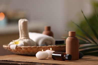 Photo of Composition with different spa products and burning candles on wooden table against blurred background, space for text