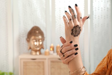 Woman with henna tattoo on hand indoors, closeup and space for text. Traditional mehndi ornament