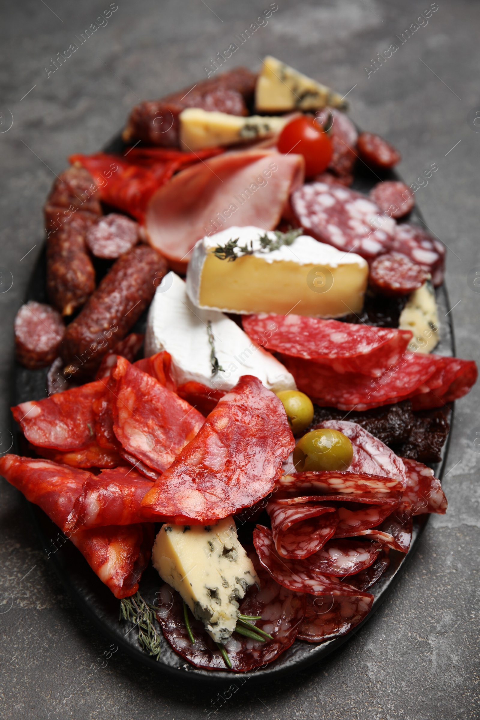 Photo of Tasty ham with other delicacies served on grey table