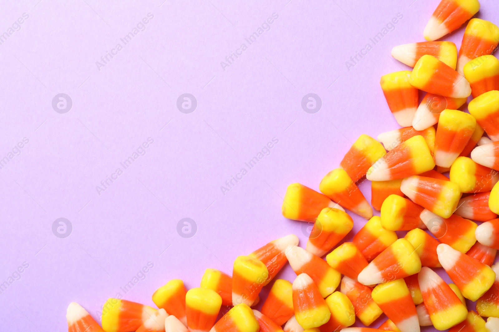 Photo of Colorful candy corns and space for text on color background, top view