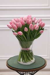 Photo of Bouquet of beautiful pink tulips in vase on table near white wall