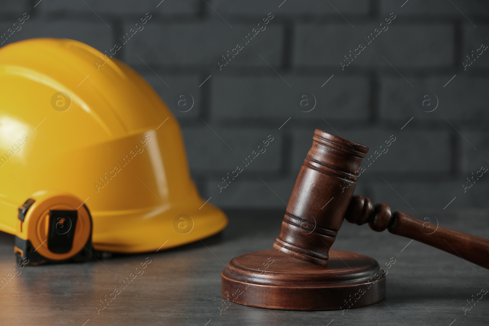 Photo of Construction and land law concepts. Judge gavel, protective helmet with tape measure on grey table