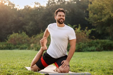 Photo of Man practicing yoga on mat in park