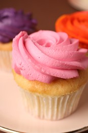 Photo of Delicious cupcakes with bright cream on plate, closeup